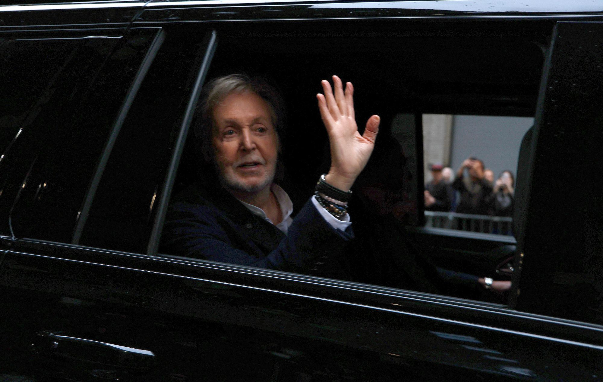 Paul McCartney waves from a car in 2026