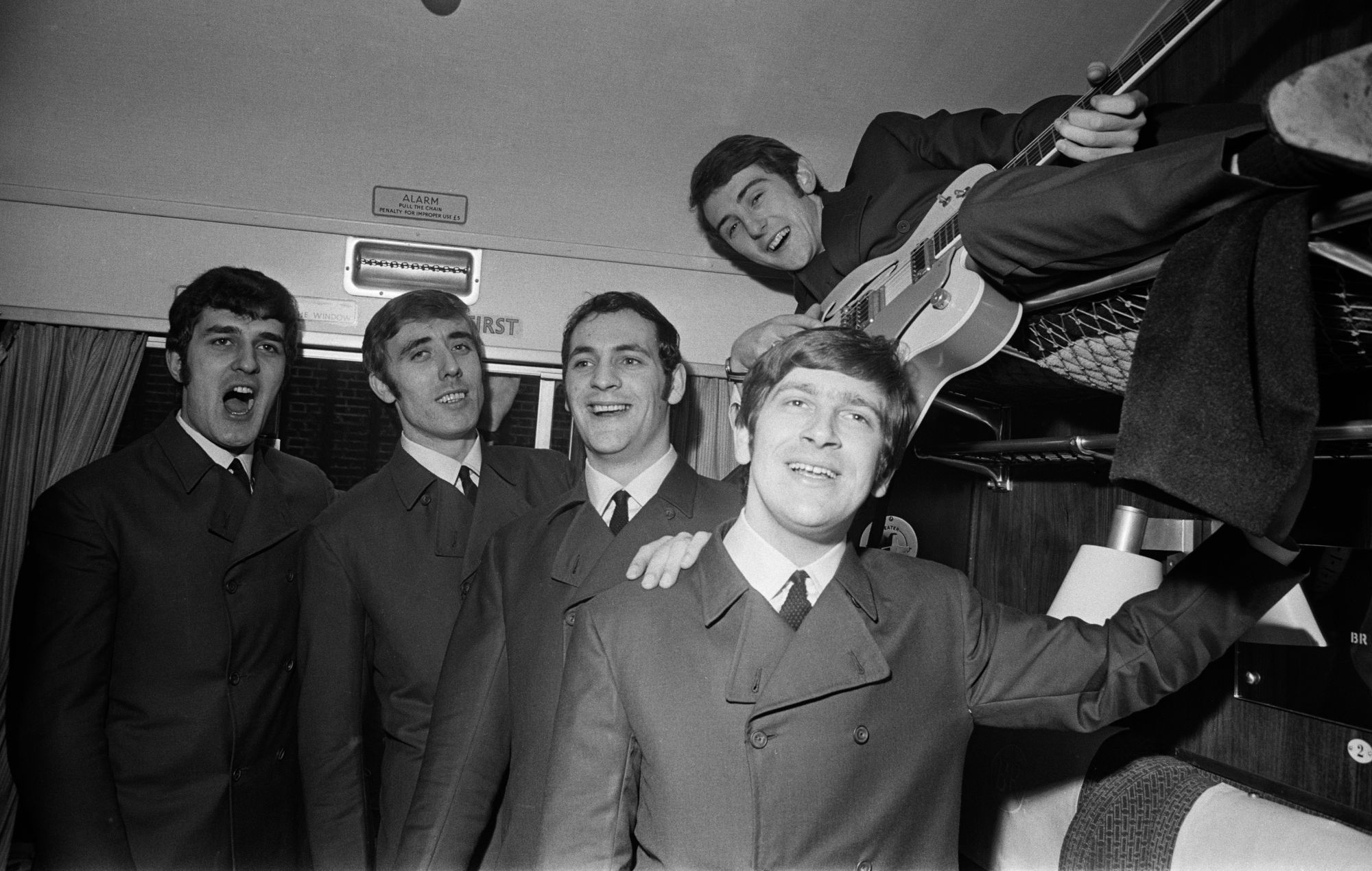 English rock band The Moody Blues pose for a photograph in a first class carriage on a train, 11th November 1964. Left to right : Ray Thomas, Clint Warwick, Mike Pinder, Graeme Edge, and Denny Laine (on shelf).