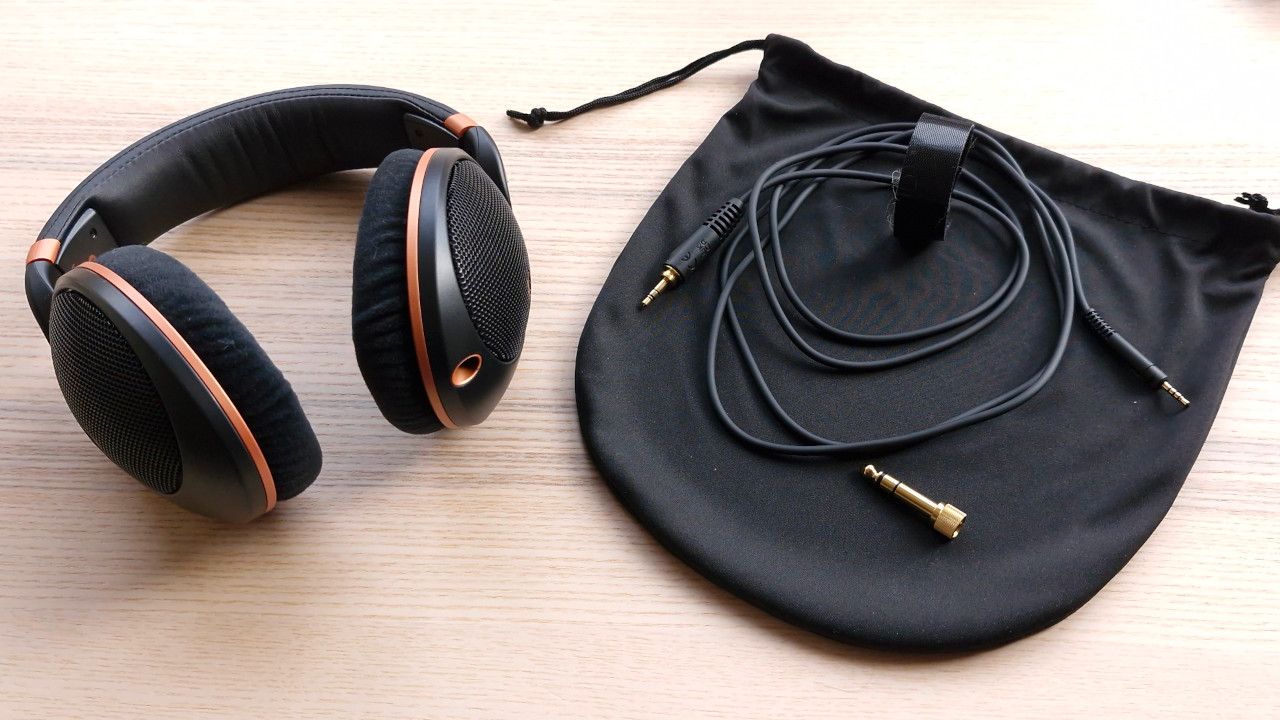 The Sennheiser HD 505 headphones on a wooden surface beside a carry case and assorted cables.