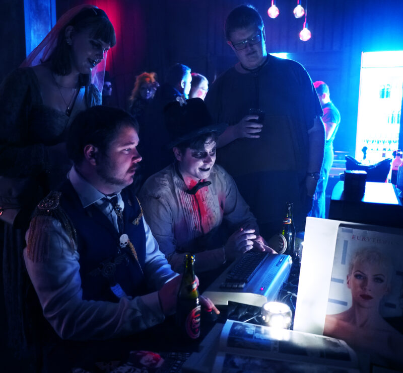 Klub Golem guests gathered around a Commodore 64 in the Eighties Corner.