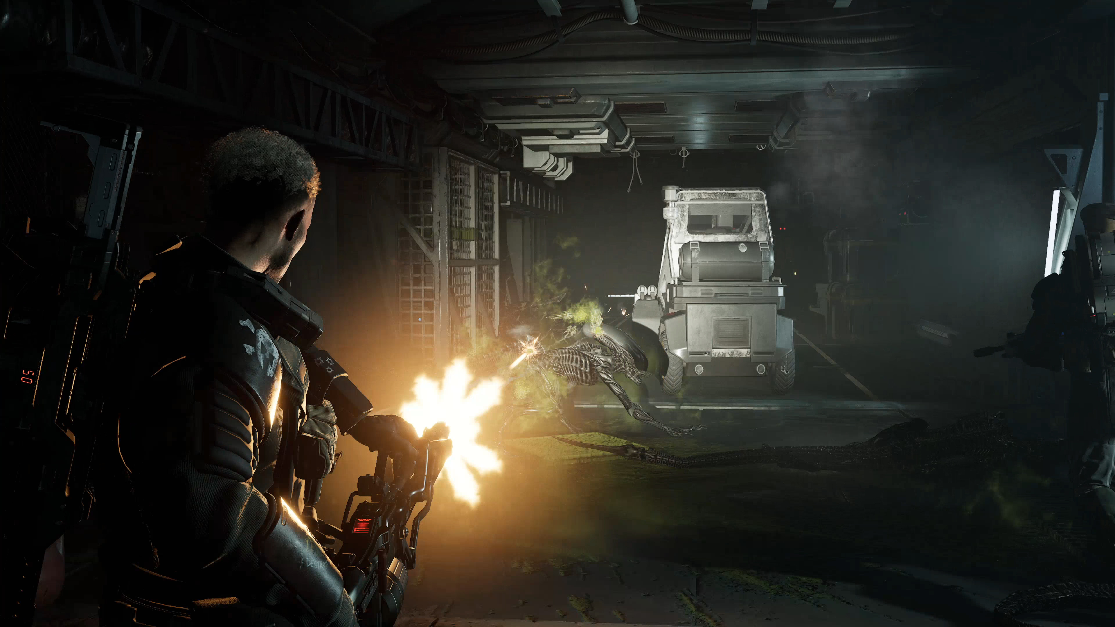 A person in a dark, smoky environment firing a weapon, with a vehicle and other equipment visible in the background.