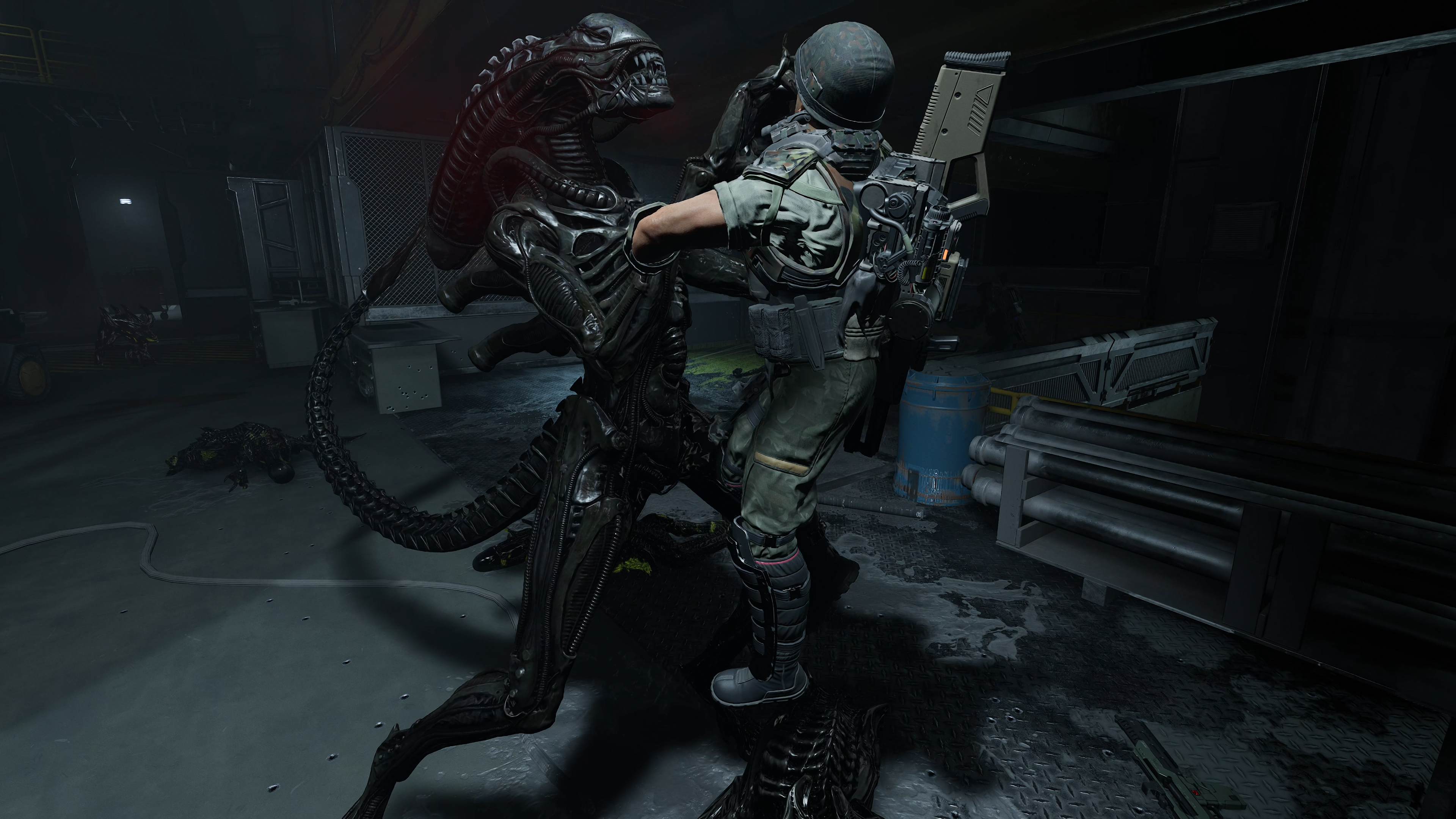 A heavily armed and armored figure, resembling an alien creature, stands in a dark, industrial setting, holding a large weapon.